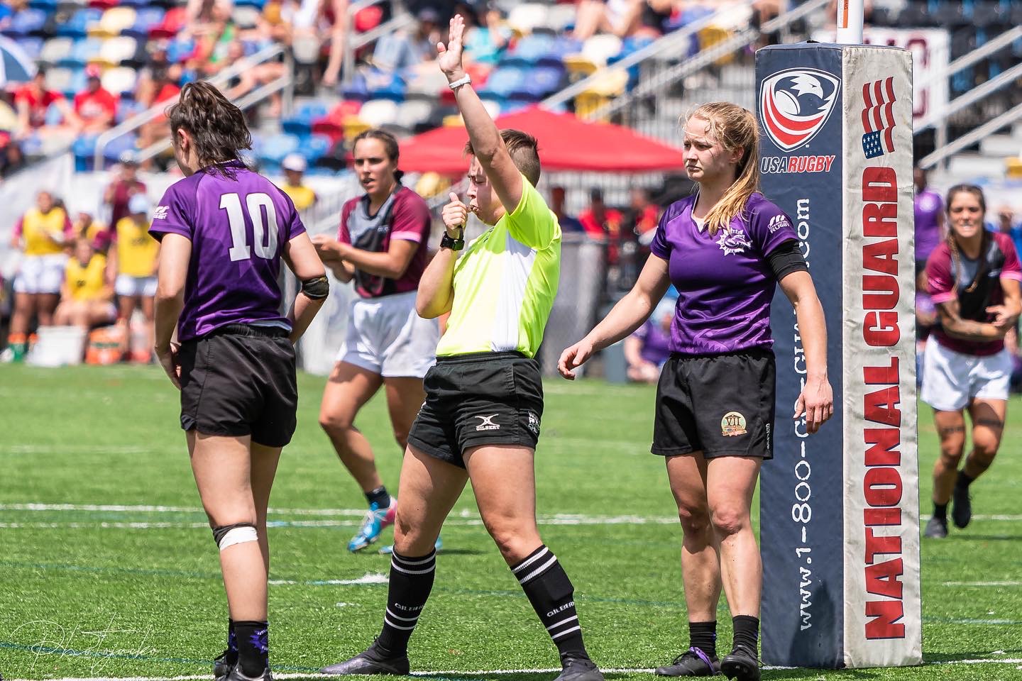 Lindsey standing in the in-goal of a rugby pitch, whistling to award the try.